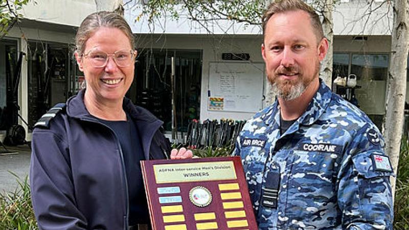Two Air Force personnel hold an award plaque facing the camera.