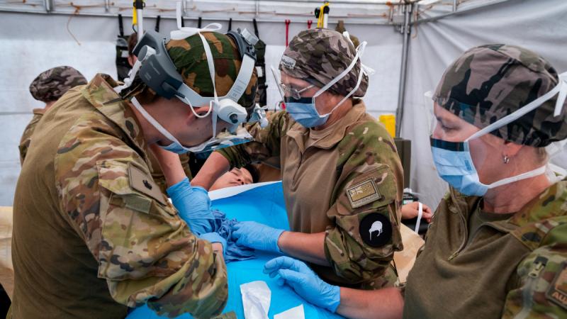 Three Army medics work on a simulated casualty on a tent. 