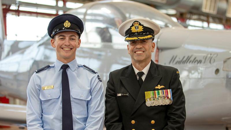 An Air Force graduate sits with his Navy commander father in front of an aircraft.