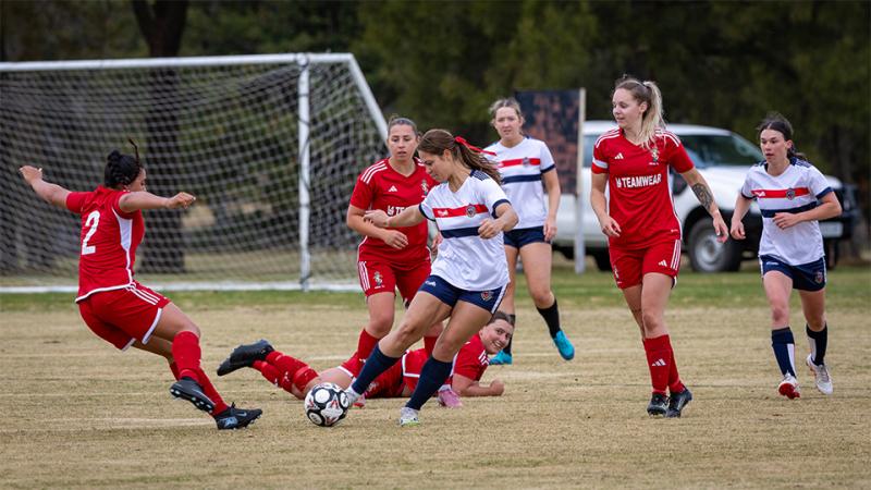 Two women's teams engage in a game of soccer.