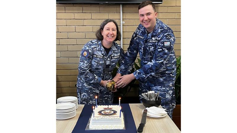 Two military personnel cut a cake together.