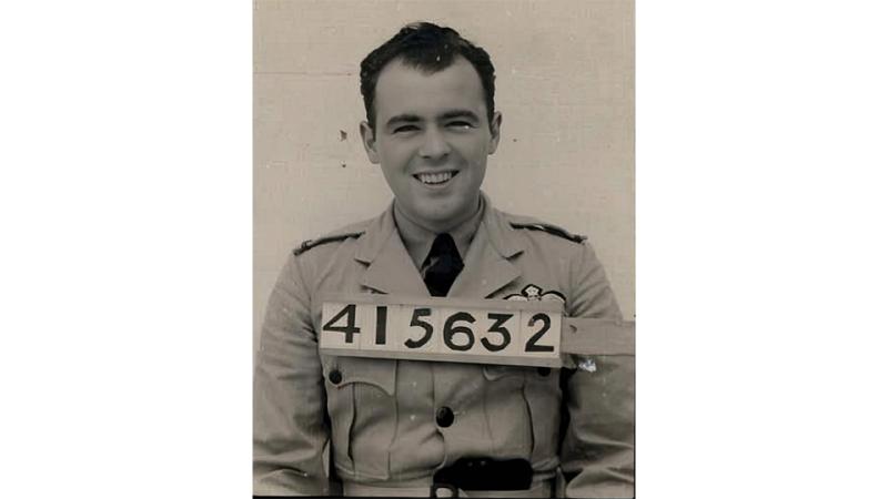 A black and white portrait of a man in military uniform with a numbered board positioned in front of him.