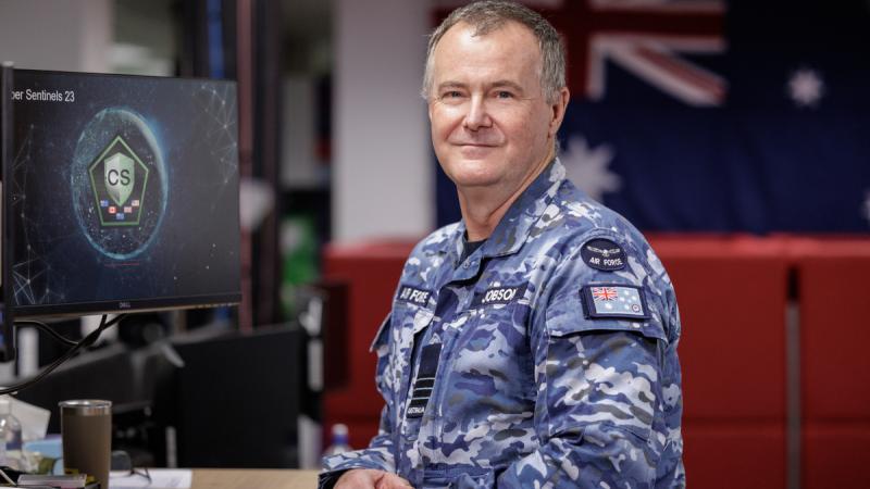 A man in Air Force uniform stands in front of a computer.