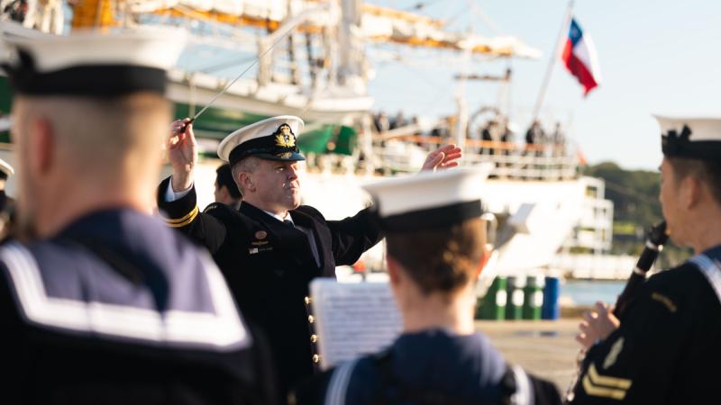 A Navy member conducts members of a Navy Band.