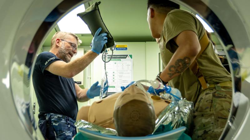 An Air Force and Army member prepare to put a dummy into a CT scanner.