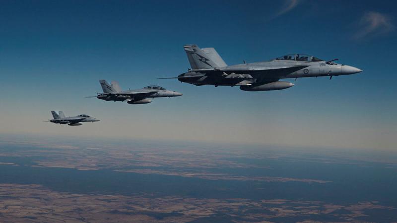 Three aircraft fly in close proximity above land.