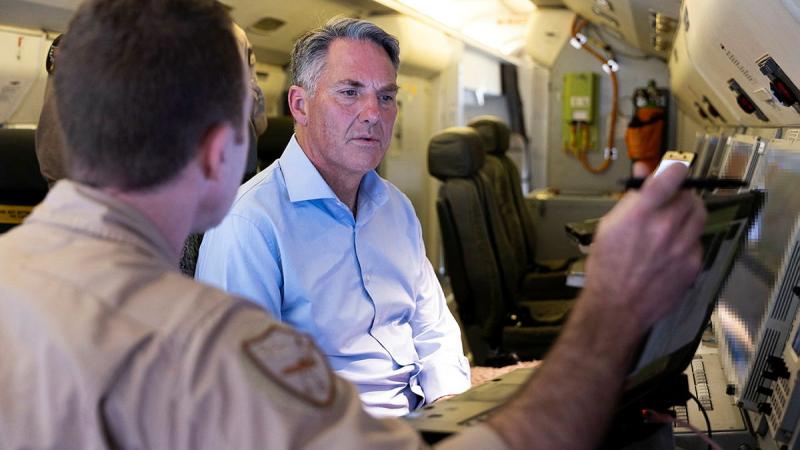 A man faces towards another as he explains the images on a video screen.