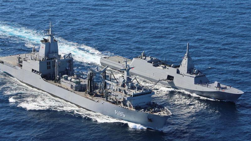 Two ships travel side by side in a deep blue sea.