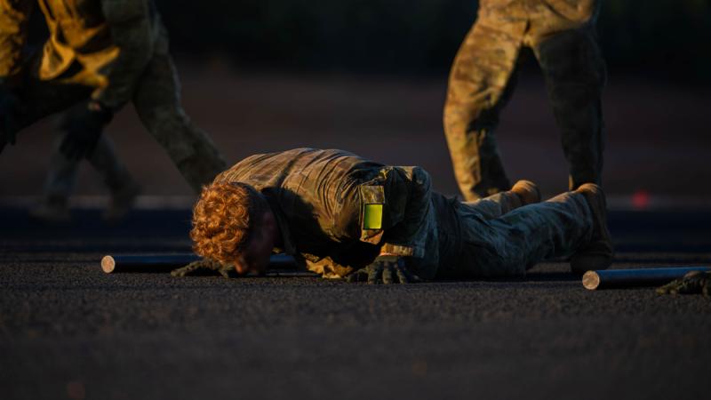 An Australian Defence Force candidate vying to become a Special Forces Operator or Combat Controller holds the push up position low to the ground in the dark of the night, completing a physical assessment.