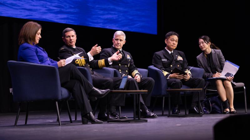 Four people sitting on a stage, talking.