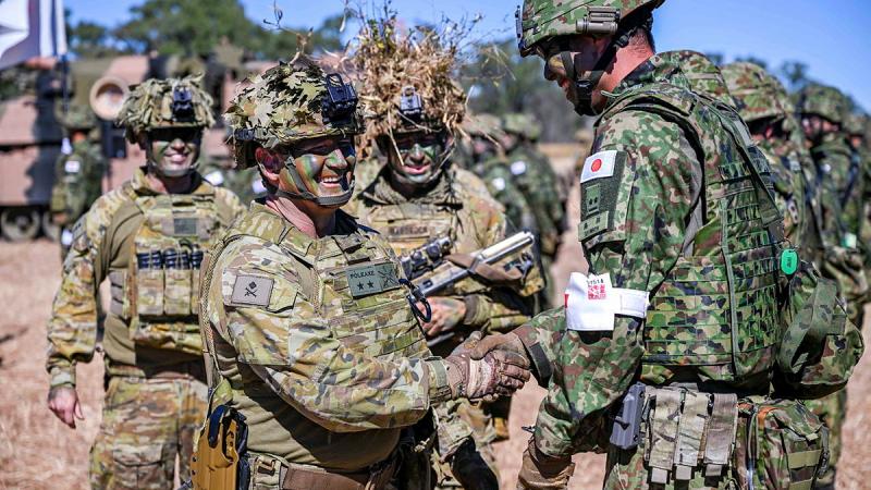 Army personnel from different countries greet each other.