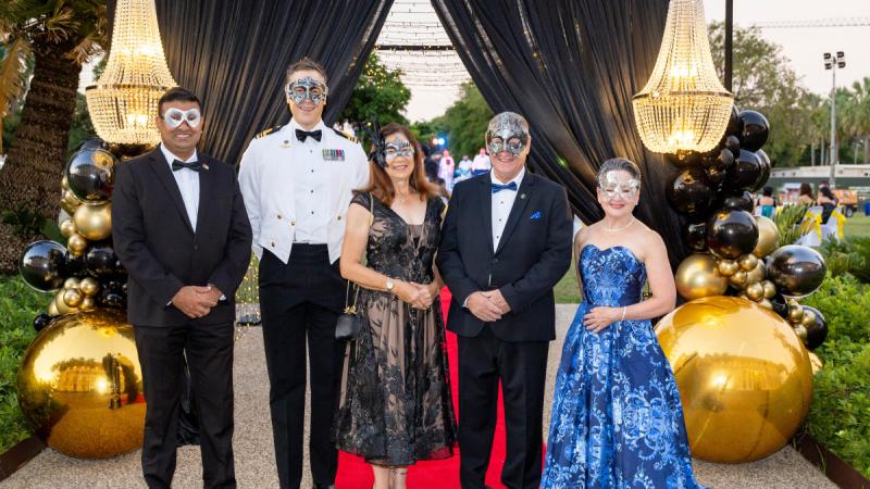 Five guests face the camera wearing masquerade masks.