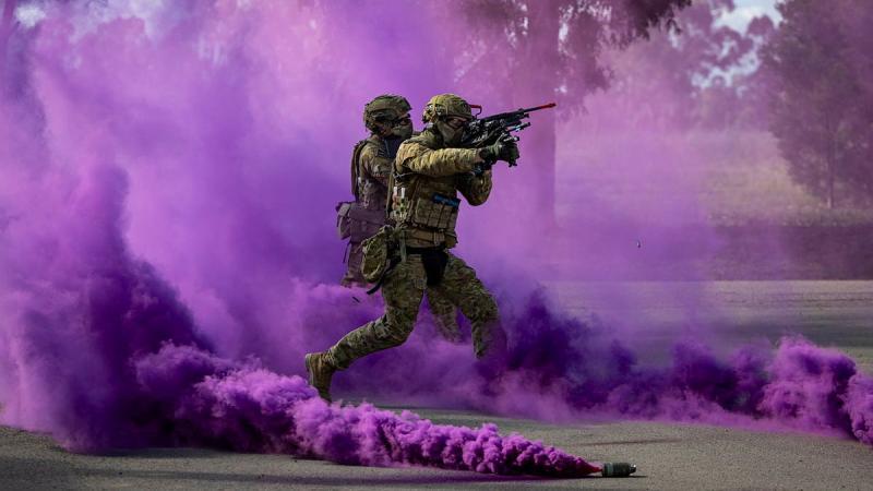 Two soldiers with guns run through purple smoke.
