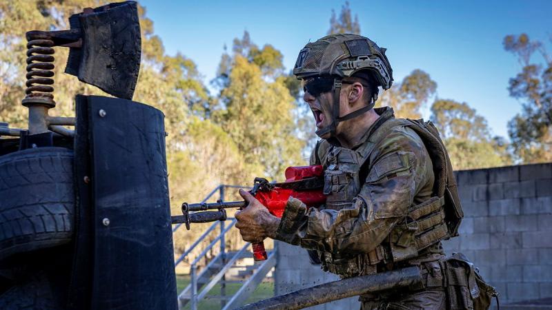 A soldiers pushes his bayonet through a target.