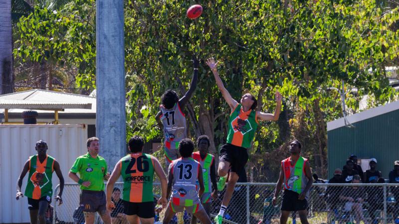 The people jump for a football while other team members stand around.