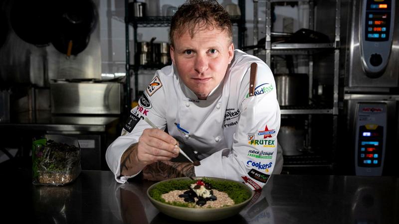 A chef leans over a plate of food he has brought to life