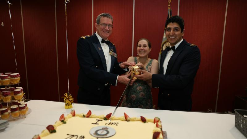Three Air Force personnel cut a 70th birthday cake