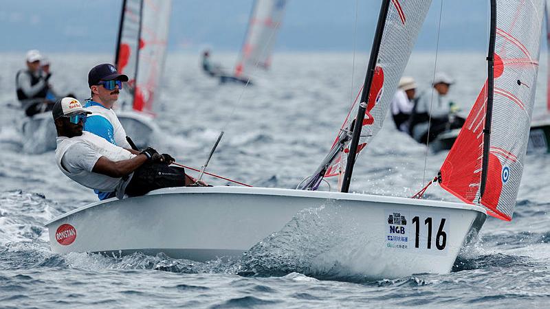Two sailors lean back in their skiff during a sailing competition.