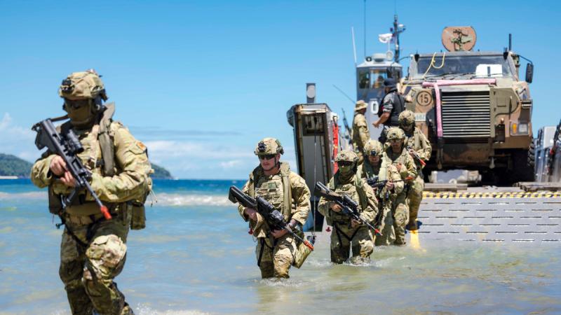 Soldiers walking through shallow water from a landing craft.