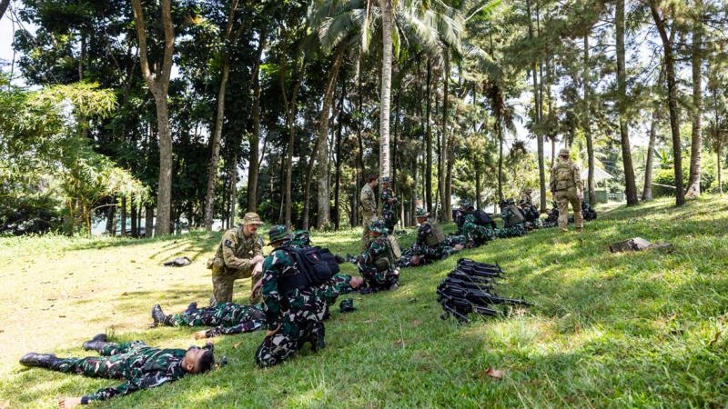 Military personnel sitting and lying on grassed areas.