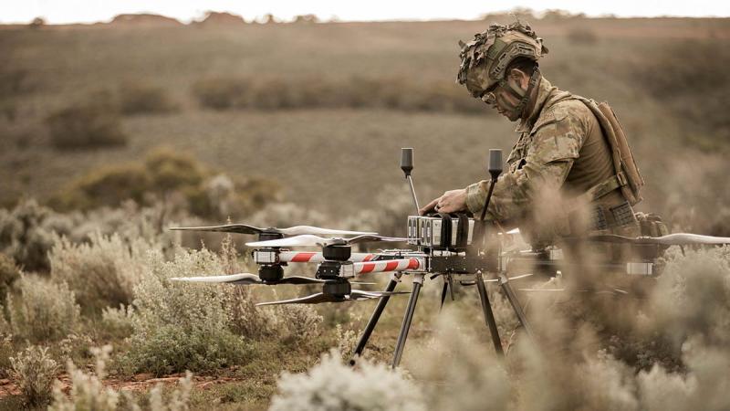 A soldier adjusts an uncrewed aerial system in the middle of the Australian bush.