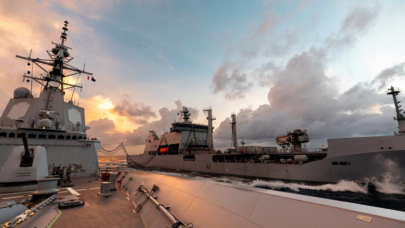 Two ships are seen connected by lines under a pinkish sky.