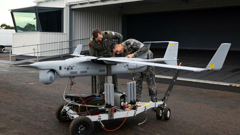Two men look closely at an aeroplane-shaped drone.