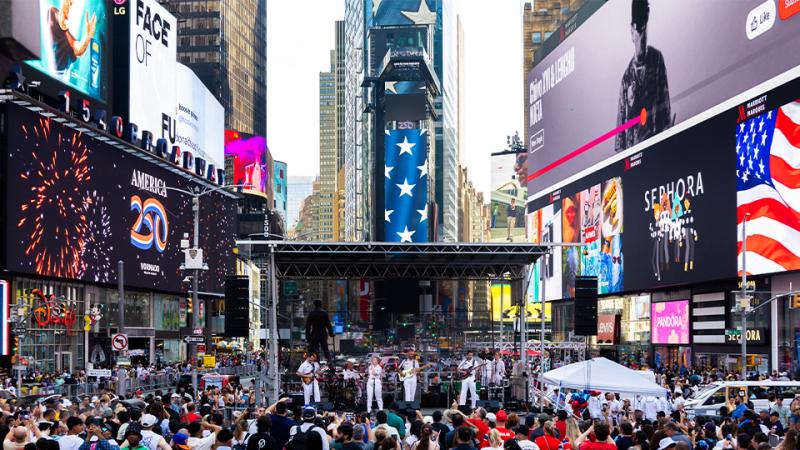 A band performs on a stage in Times Square before a crowd.