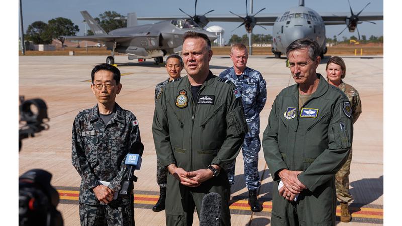 Three military men talk with the press.