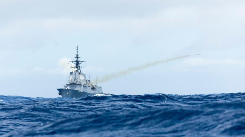 A missile fires from a warship in the sea.