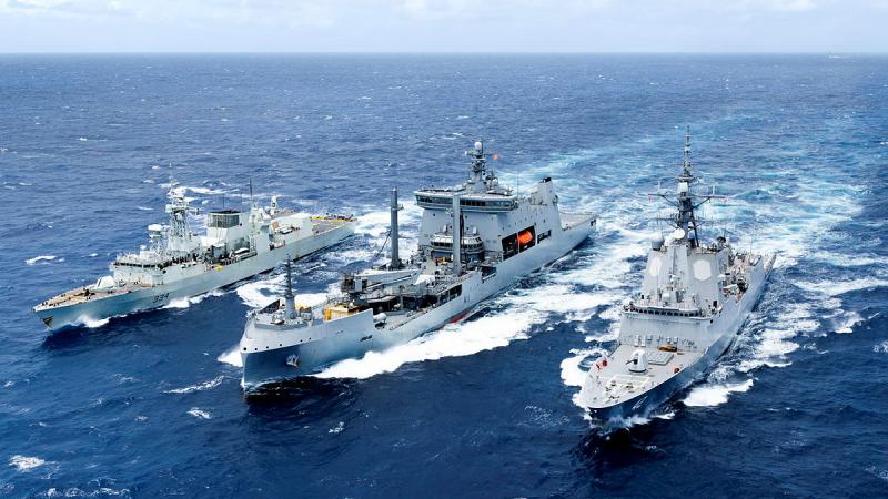 Three ships sail side-by-side in a deep blue sea.