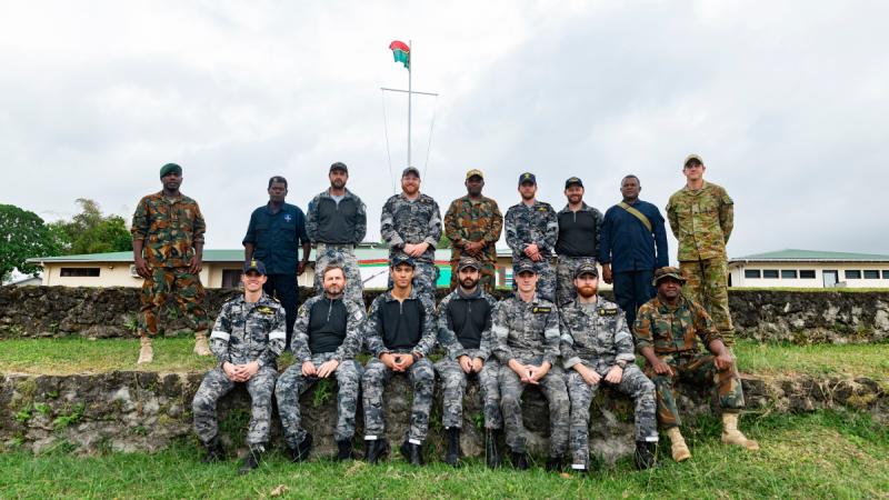 A groupf of Australian Defence Force and Solomon Islands police force members face the camera for a group photo.