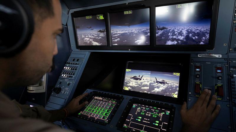 A man looks at screens showing images of aircraft.