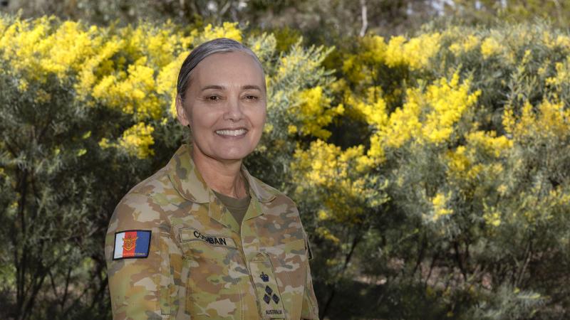 A woman in military uniform smiles at the camera.