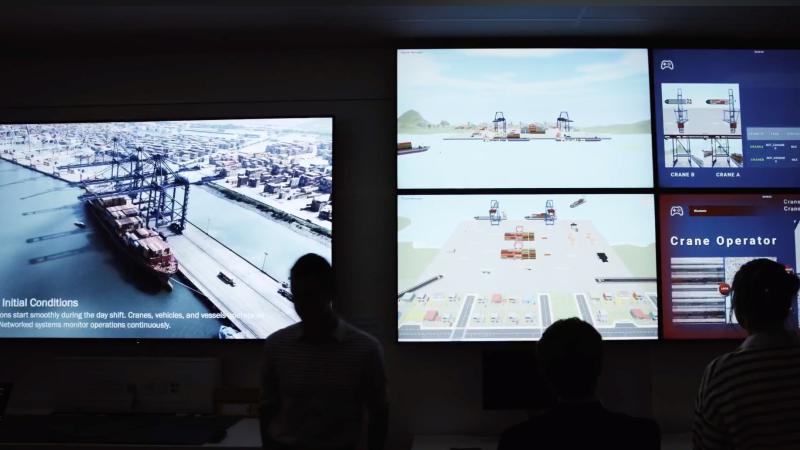 People in shadows standing in front of large television screens.