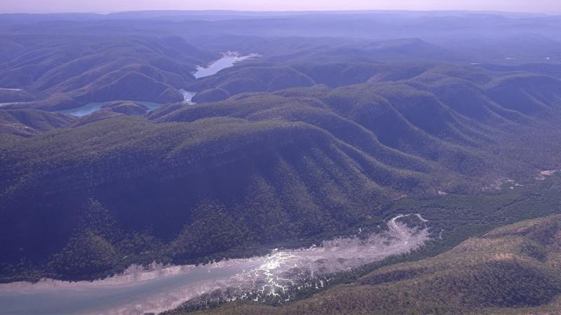 An aerial view of a green, mountainous landscape with rivers cutting through it.