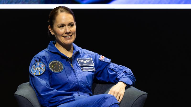 A woman in uniform sits in an armchair and smiles.